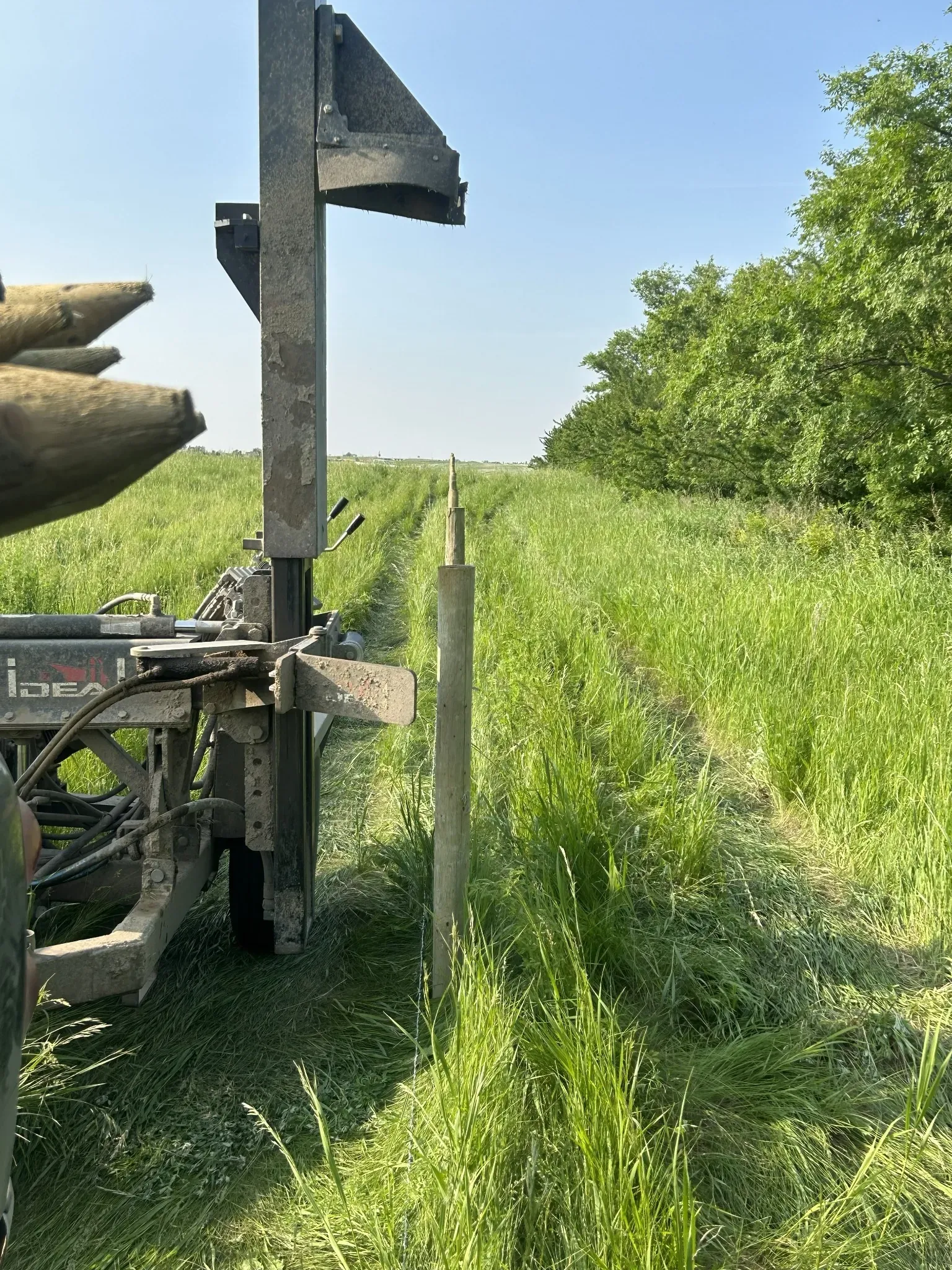 Post pounder driving fence posts into Saskatchewan prairie on a Front Line Fencing jobsite