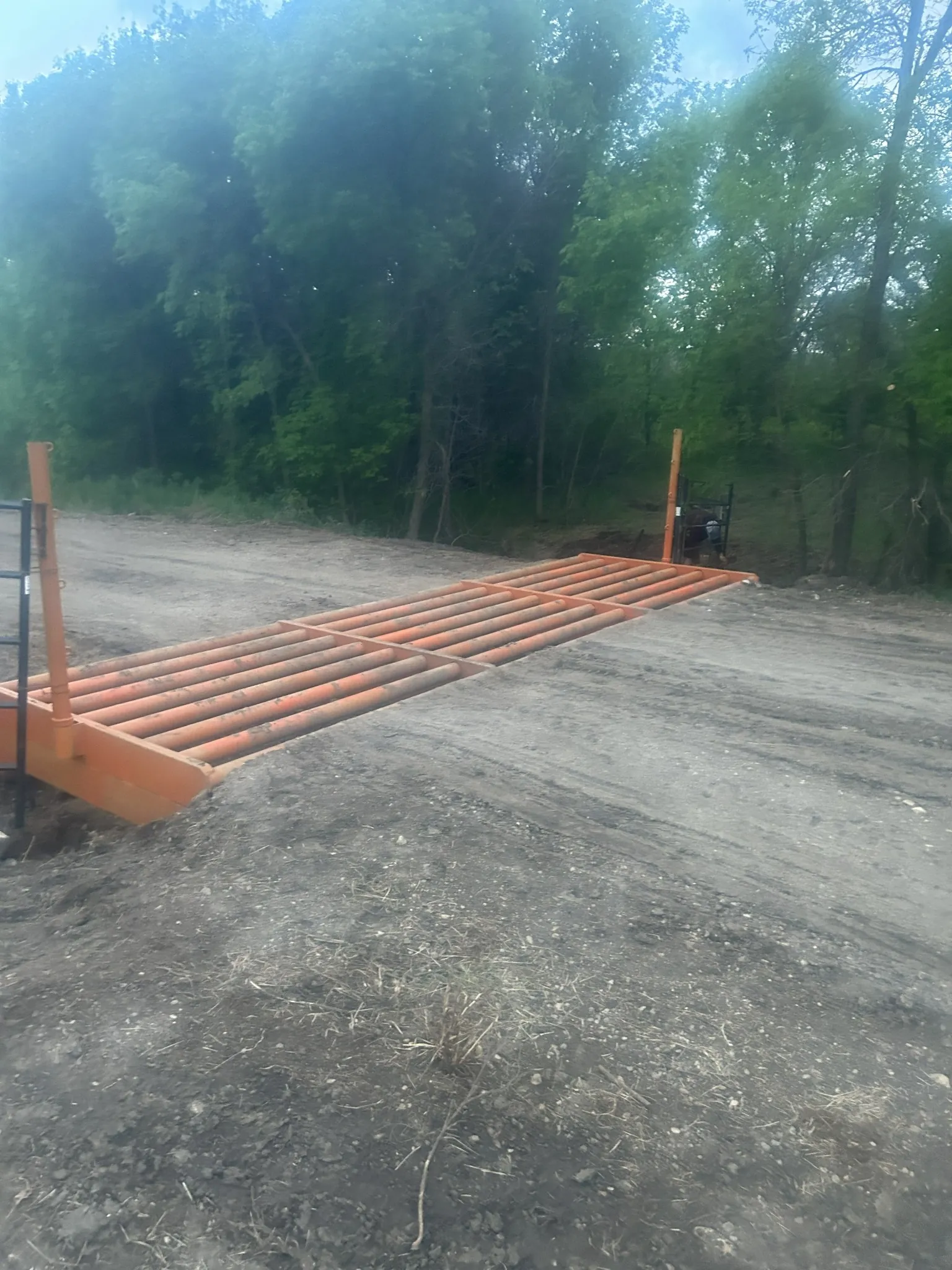 Texas gate installation on a rural access road surrounded by trees